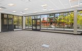 An empty room with large windows and a carpet looking out to the amphitheater.
